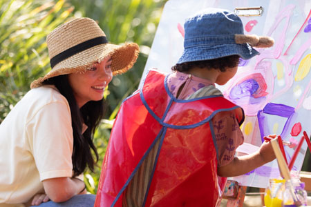 Ella, an educator, painting with a young kindy child.