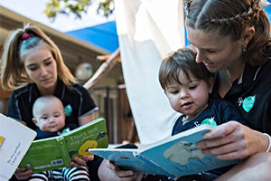 Tahleah and Lara reading books outside to children
